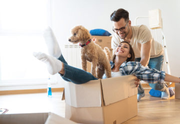 Young playful couple at their new home with dog