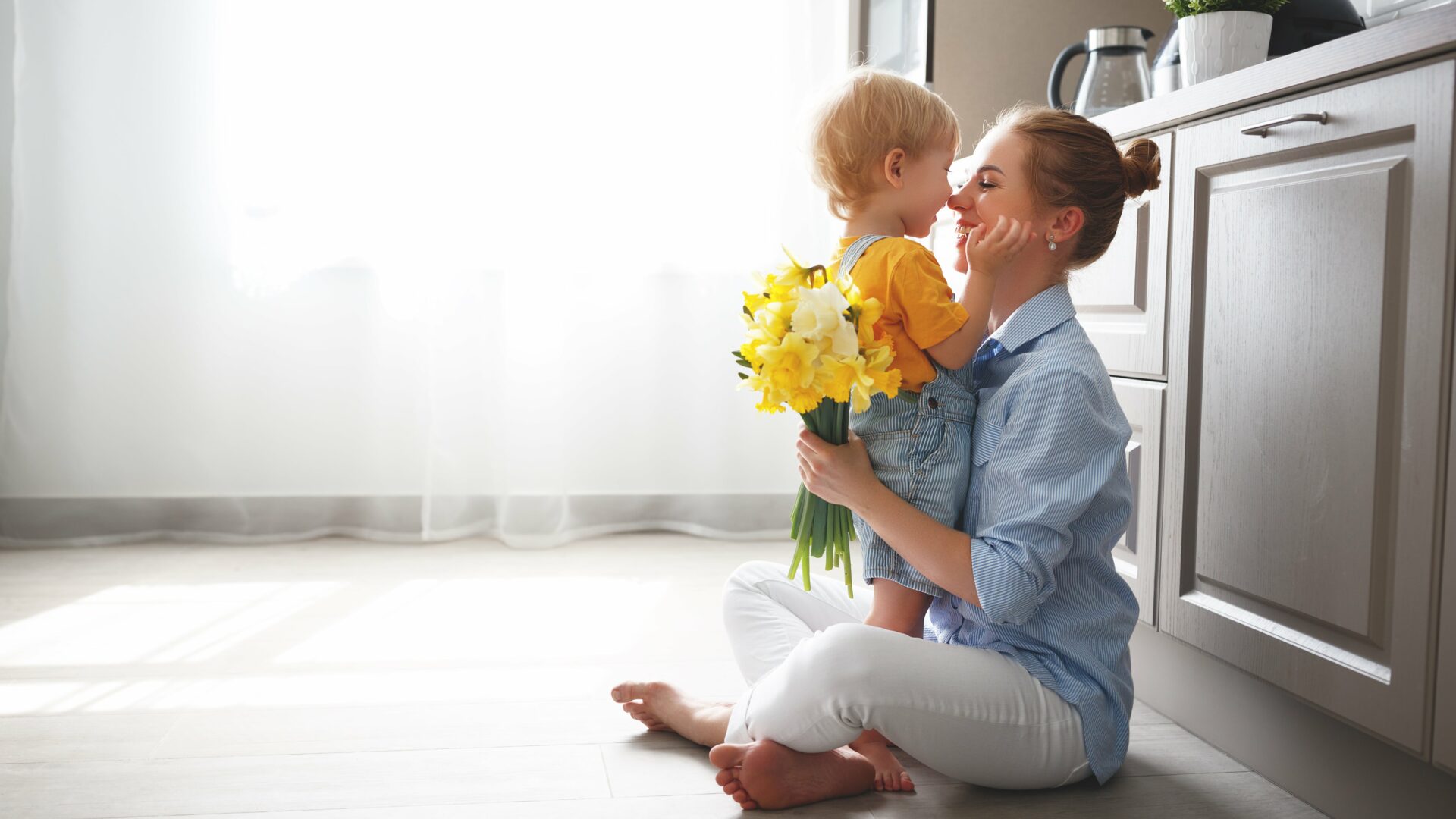 mother and child sitting in the kitchen with flowers