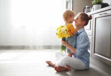 mother and child sitting in the kitchen with flowers