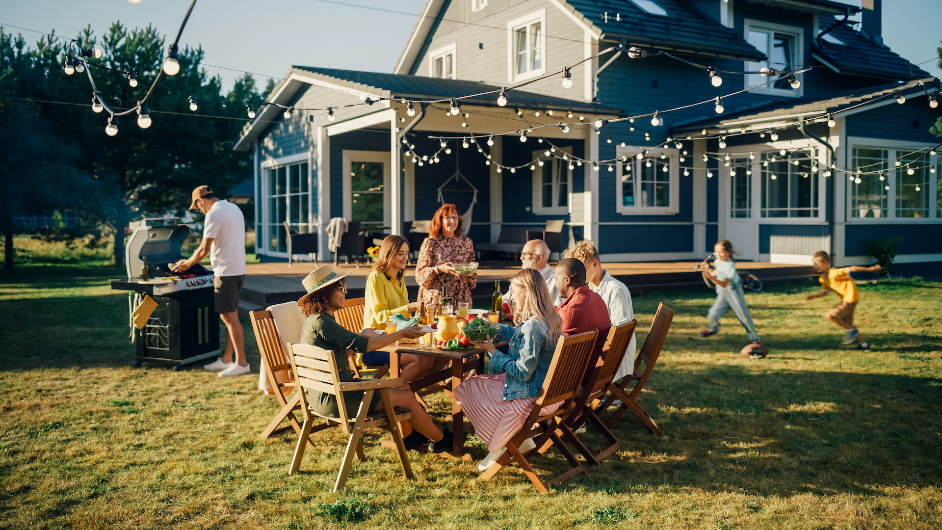 Stock photo of a family enjoying a BBQ outdoors in their backyard