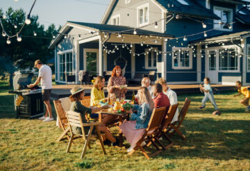 Stock photo of a family enjoying a BBQ outdoors in their backyard