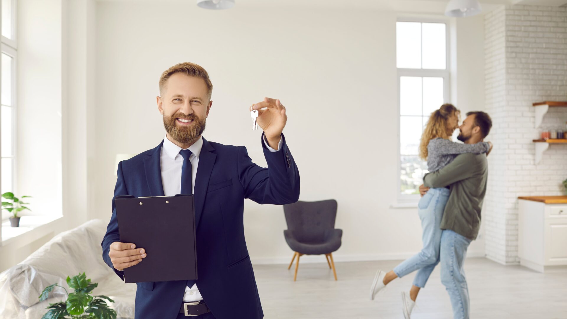 broker with keys for happy couple buying home