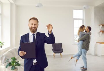 broker with keys for happy couple buying home